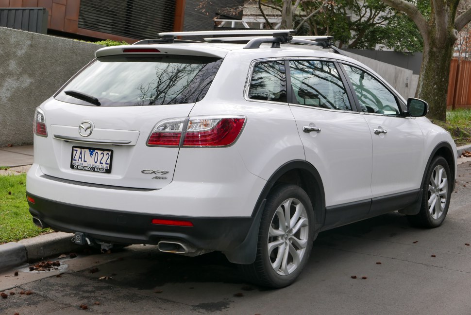 Rear side view of white SUV with roof rack and modern taillights