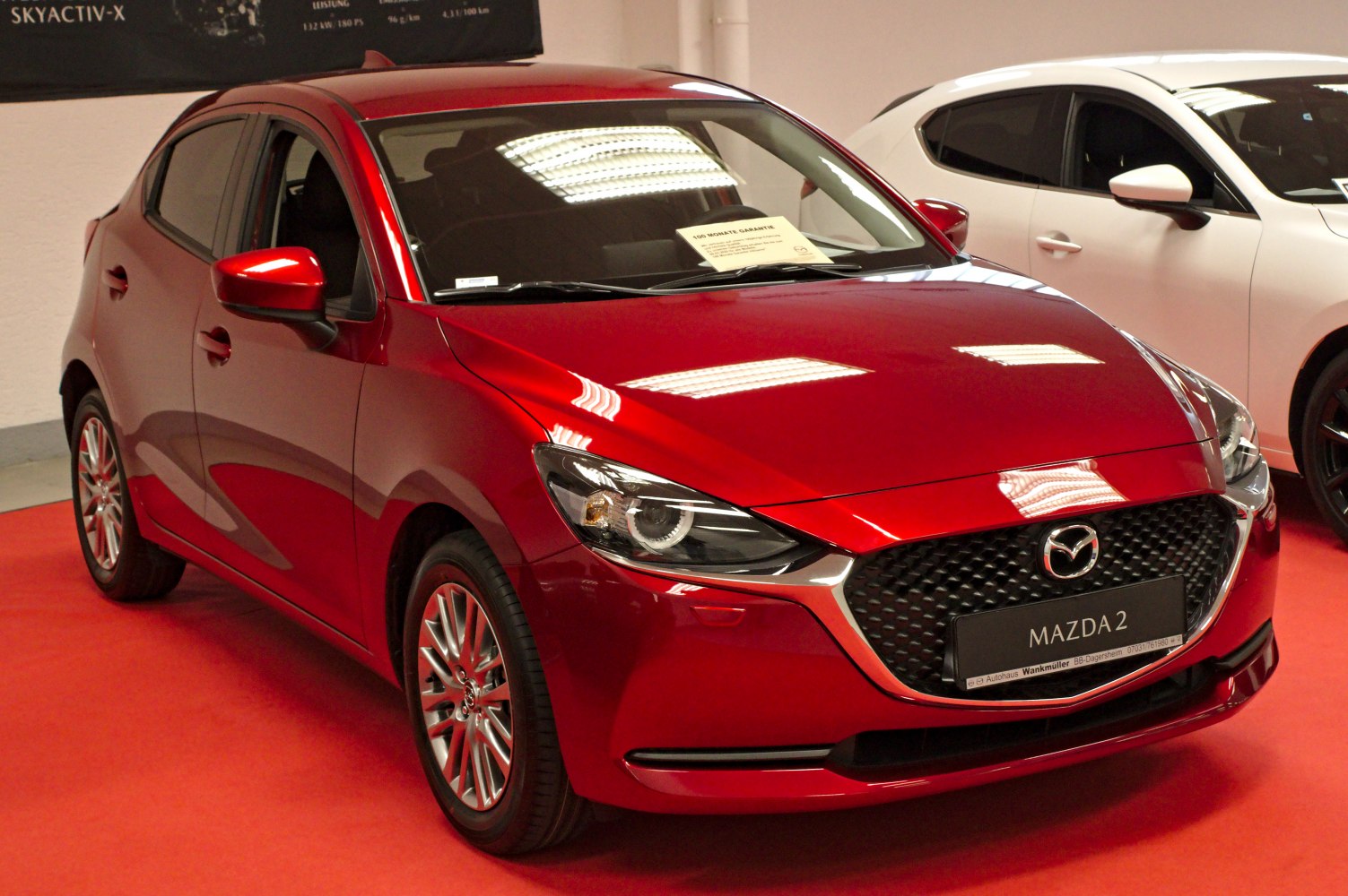 Red compact hatchback with sleek front grille and sharp headlights
