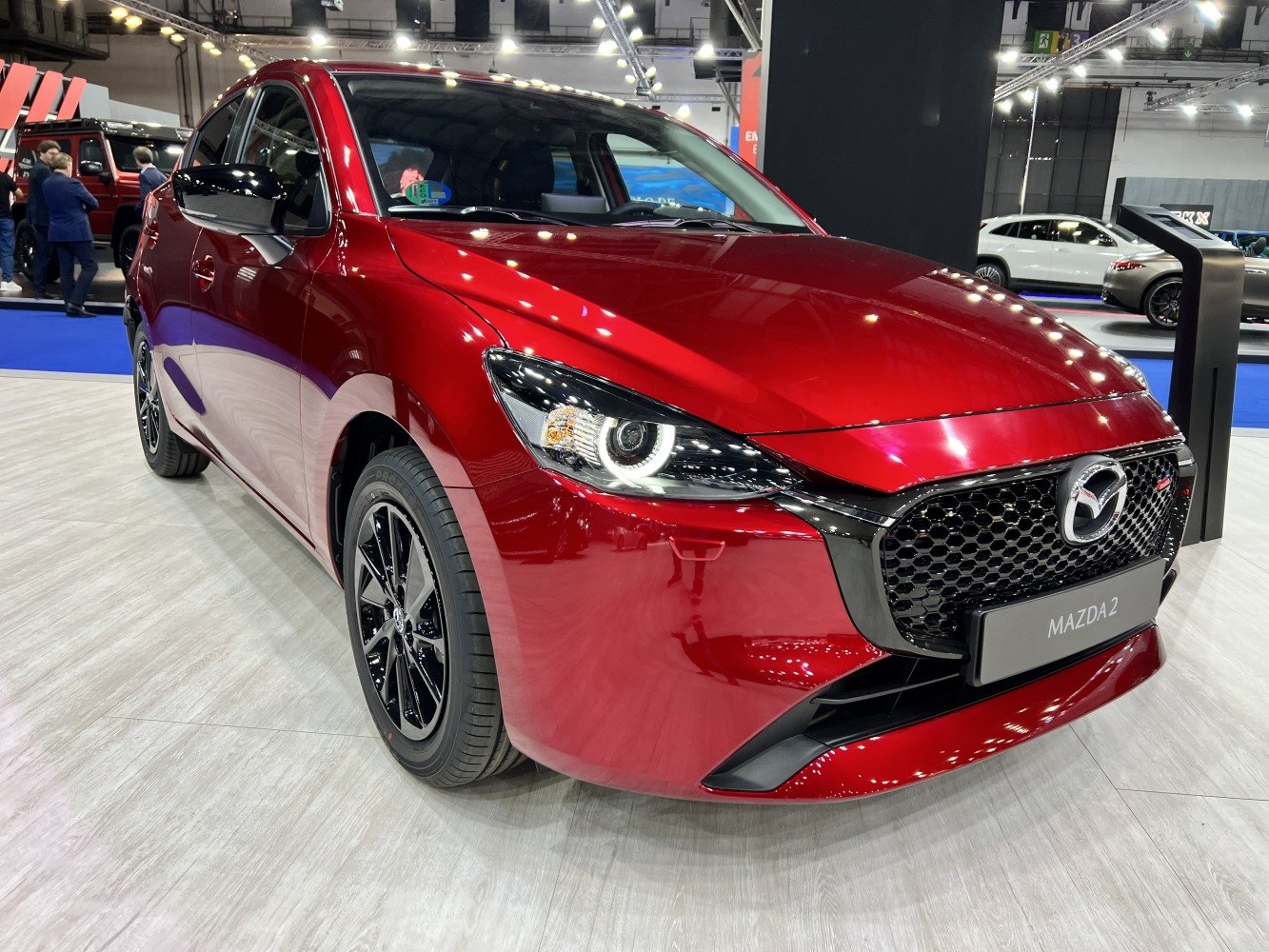 Red compact hatchback with sporty LED headlights and black honeycomb grille