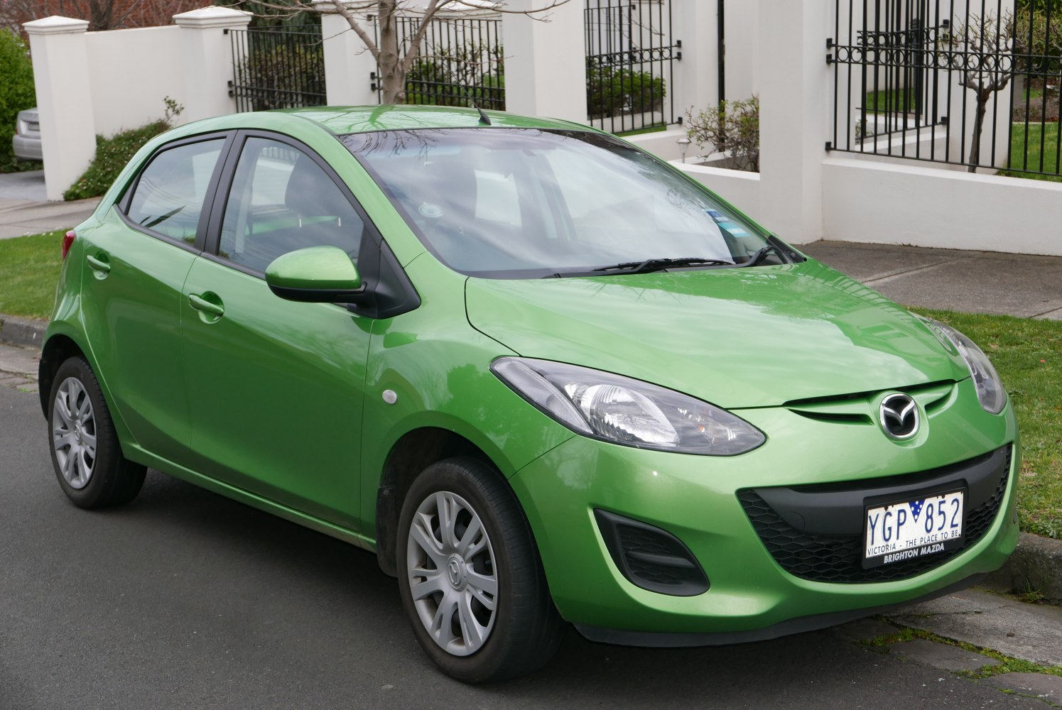 Front side view of a green hatchback with distinctive headlights and side mirrors