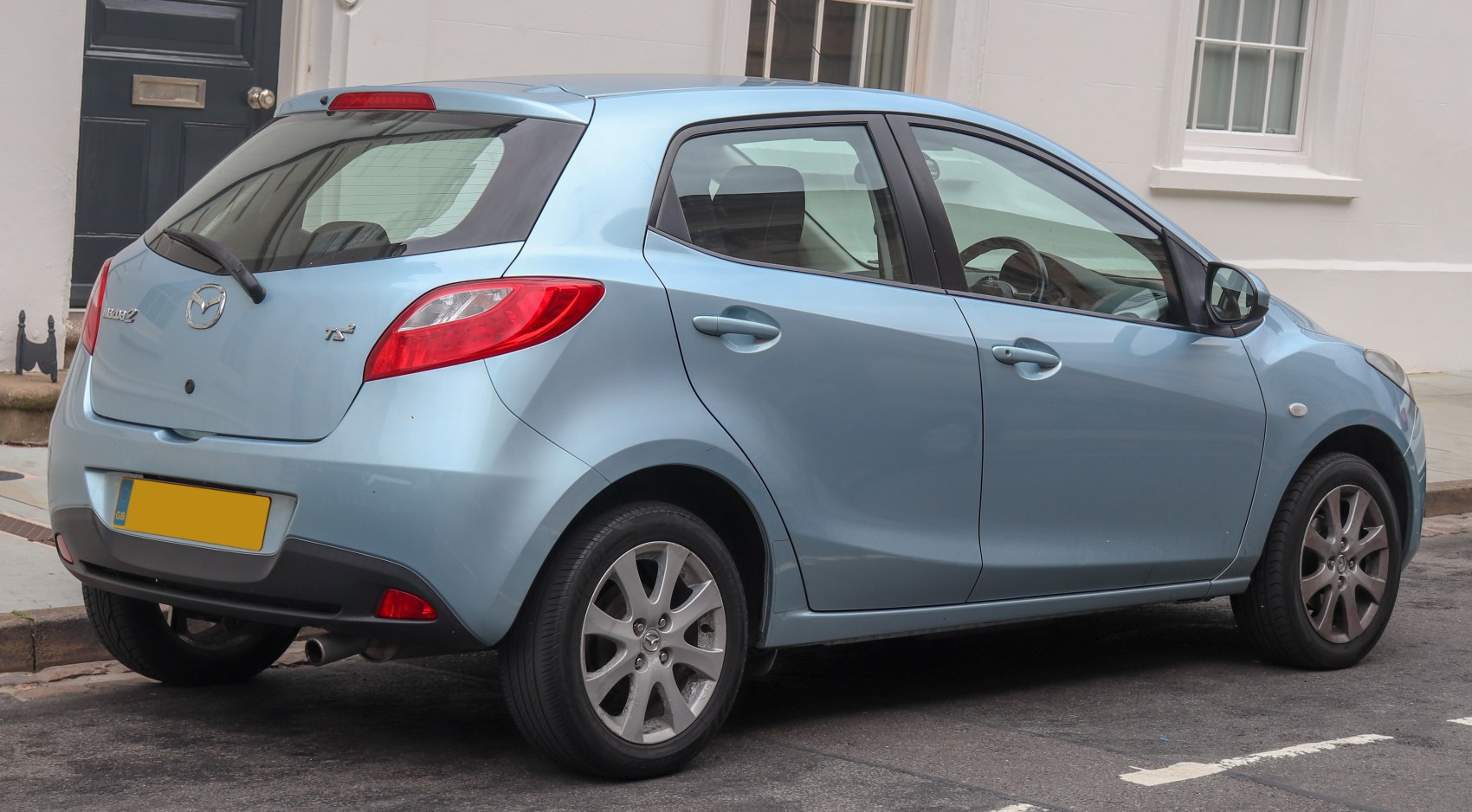 Rear and side view of a blue compact hatchback with alloy wheels and distinctive tail lights