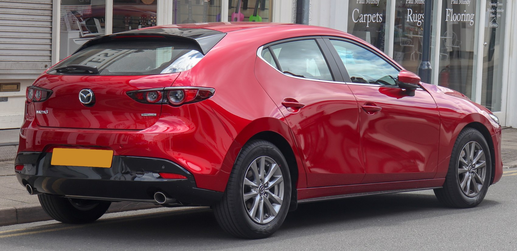Red hatchback rear and side view with dual exhaust and sporty taillights