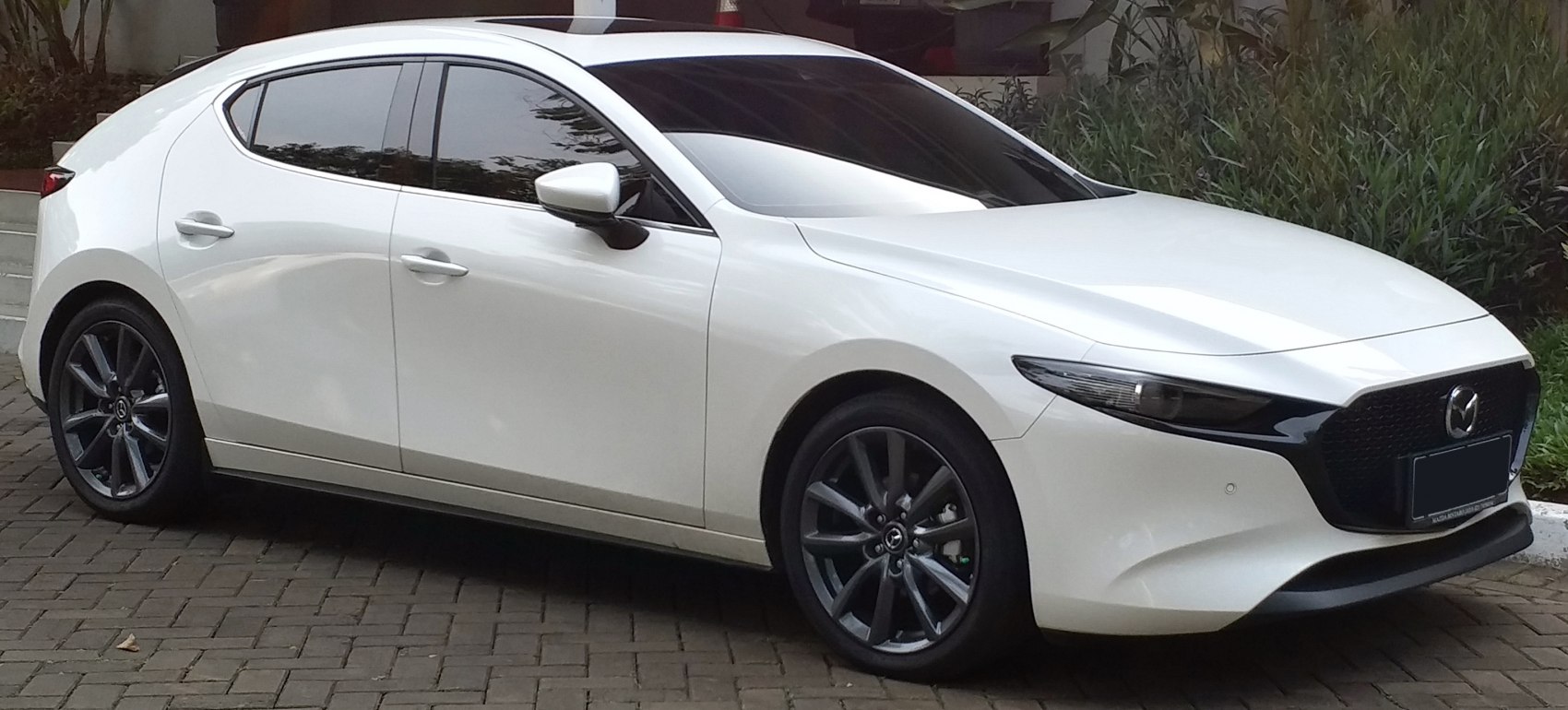 White hatchback viewed from front-side with sleek design and sporty wheels