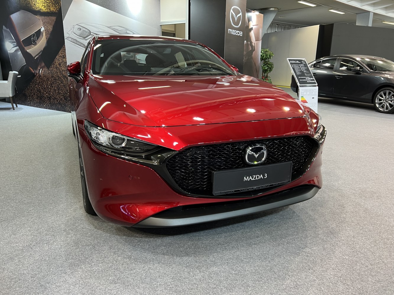 Red hatchback with signature Mazda grille and sleek headlights
