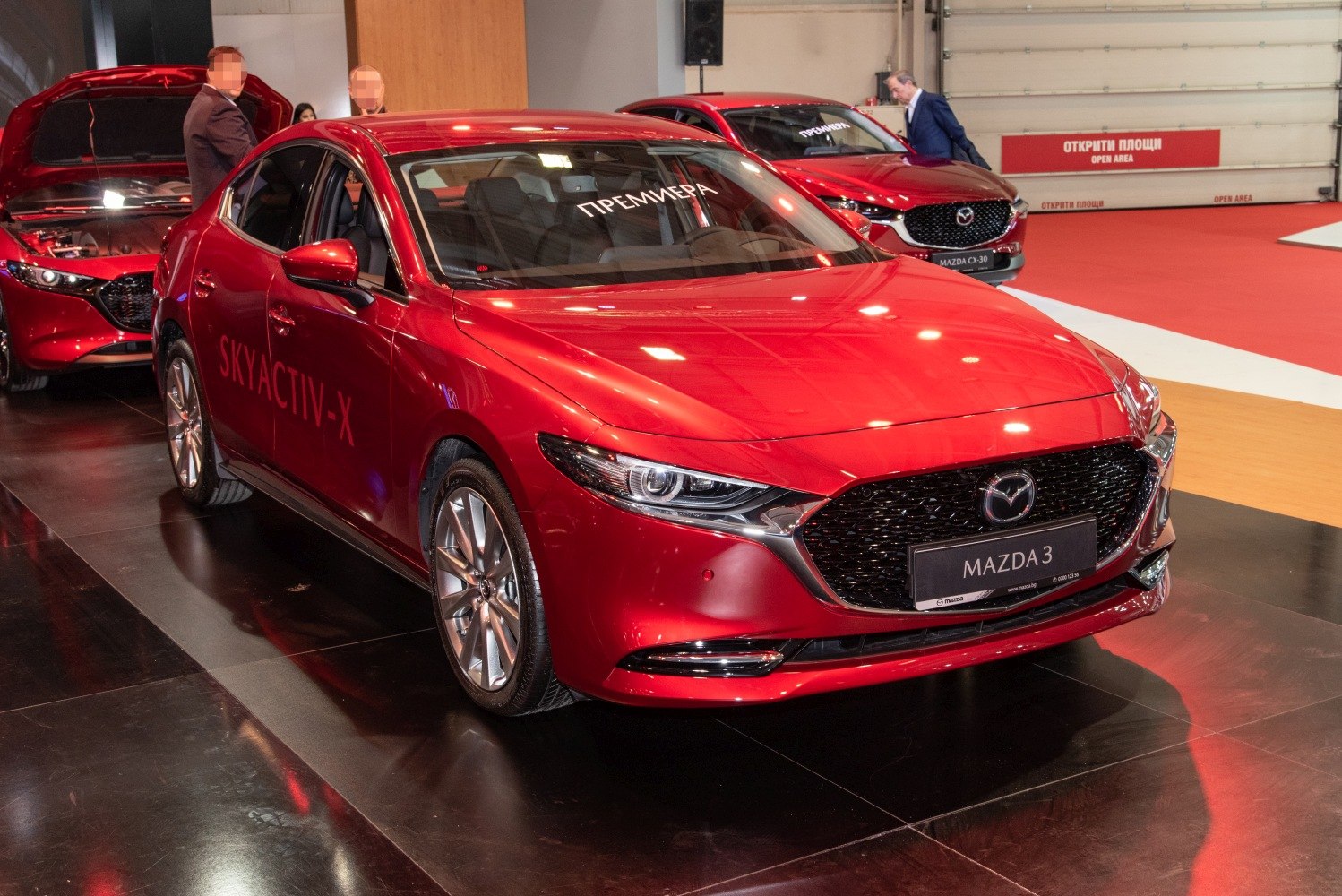 Red sedan with sleek front grille and Skyactiv-X branding