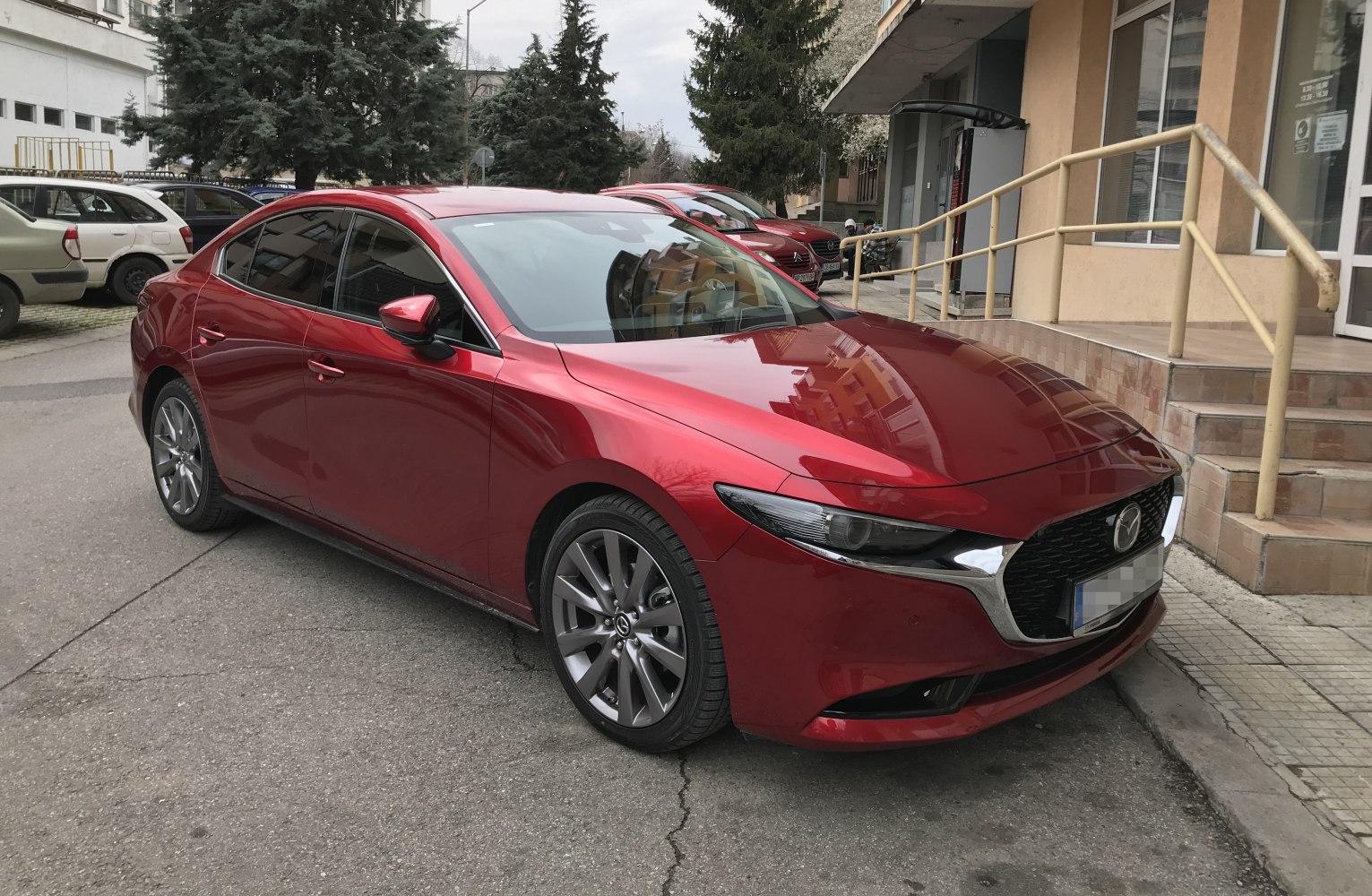 Red sedan front side view with alloy wheels and sleek design