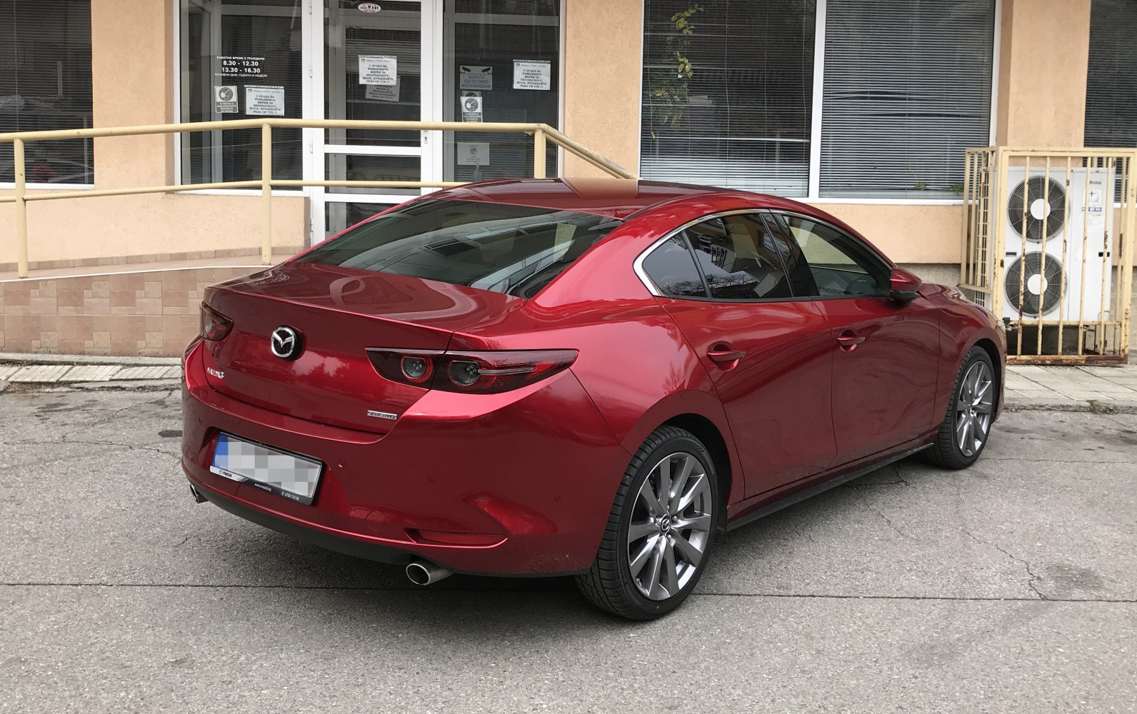 Red sedan rear side view with LED tail lights and dual exhaust.