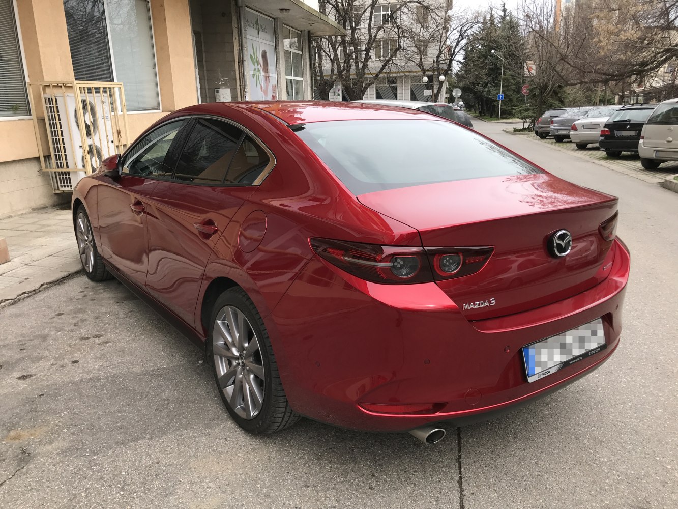 Red sedan rear with distinctive sleek taillights and alloy wheels