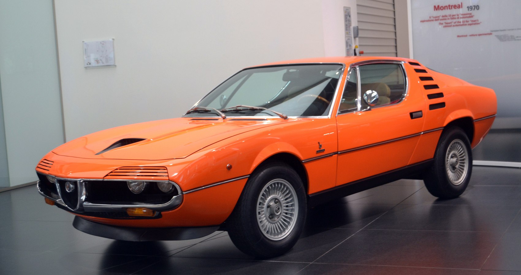 Orange classic sports car with distinctive hood vent and side window stripes