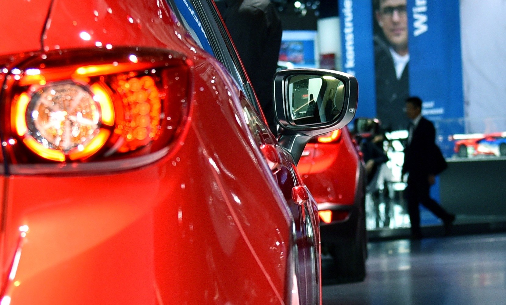 Close-up of a red car's rear taillight and side mirror.