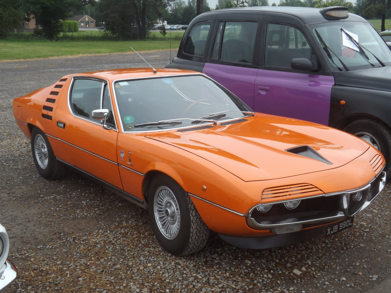 Orange sporty coupe with distinctive headlight grilles and rear side ventilation slats
