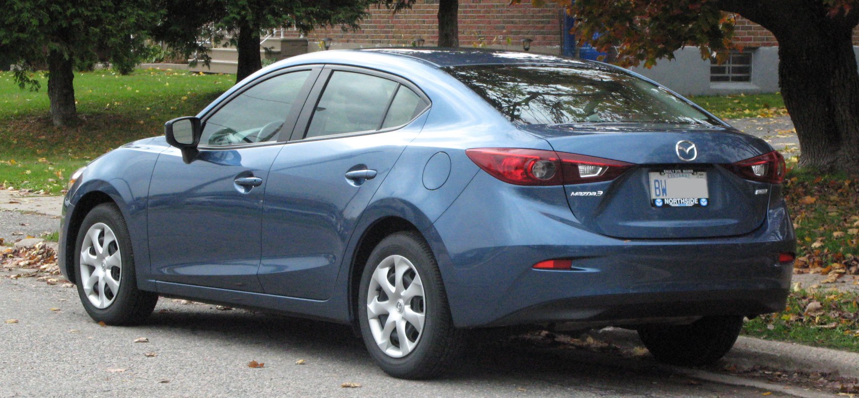 Rear and side view of a blue compact sedan with distinctive tail lights.