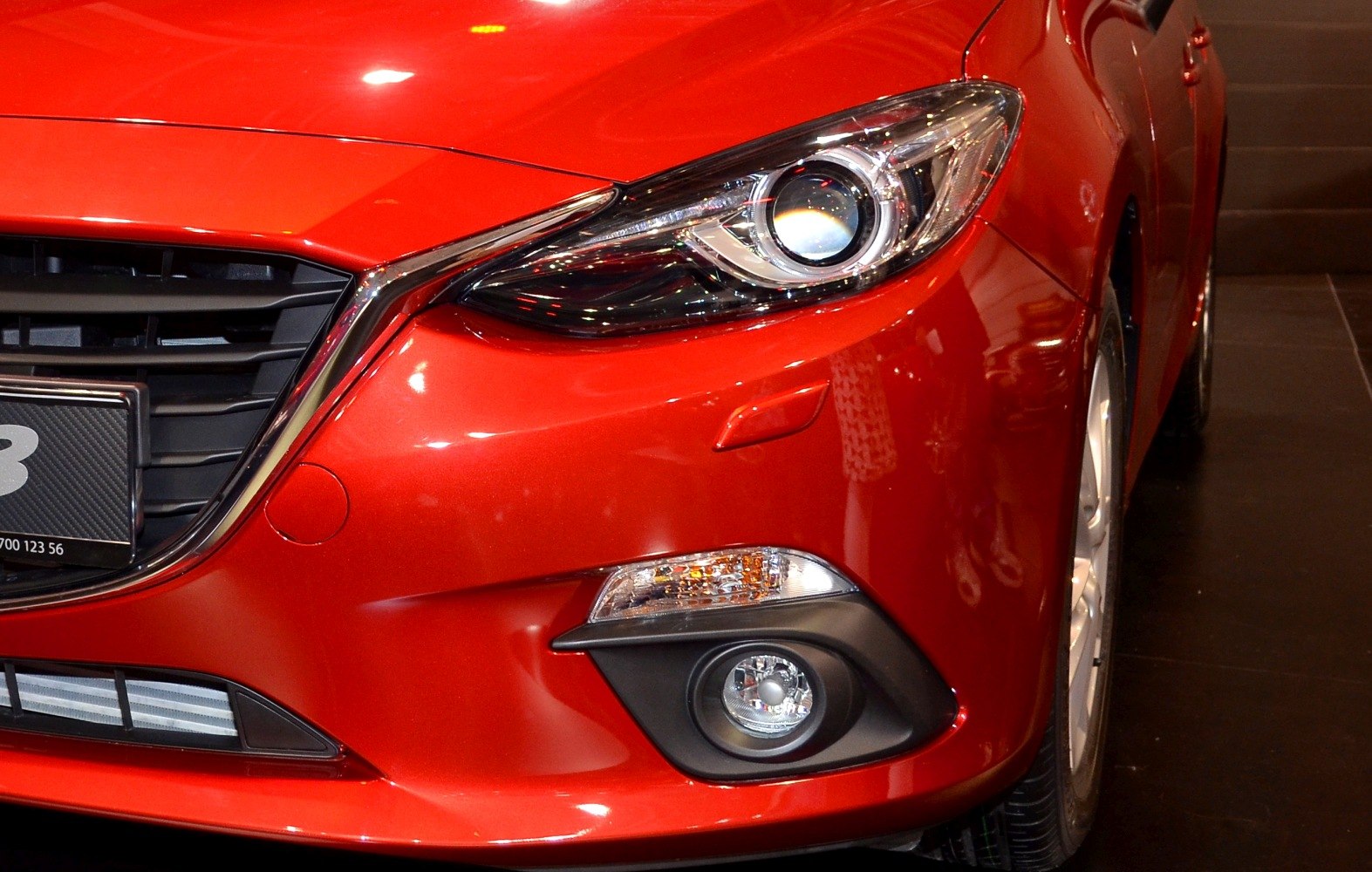 Front headlight, grille, and fog light close-up on red hatchback