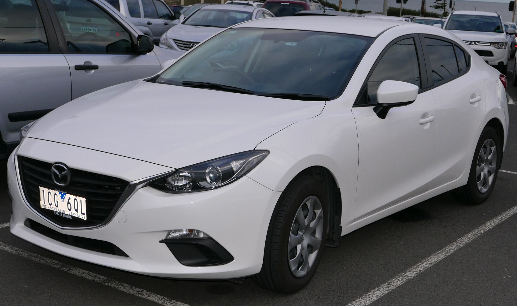 Front three-quarter view of a white sedan with sleek headlights and aerodynamic design