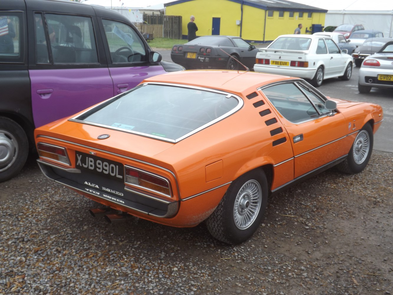 Orange vintage sports coupe with distinctive black rear louvers and alloy wheels.