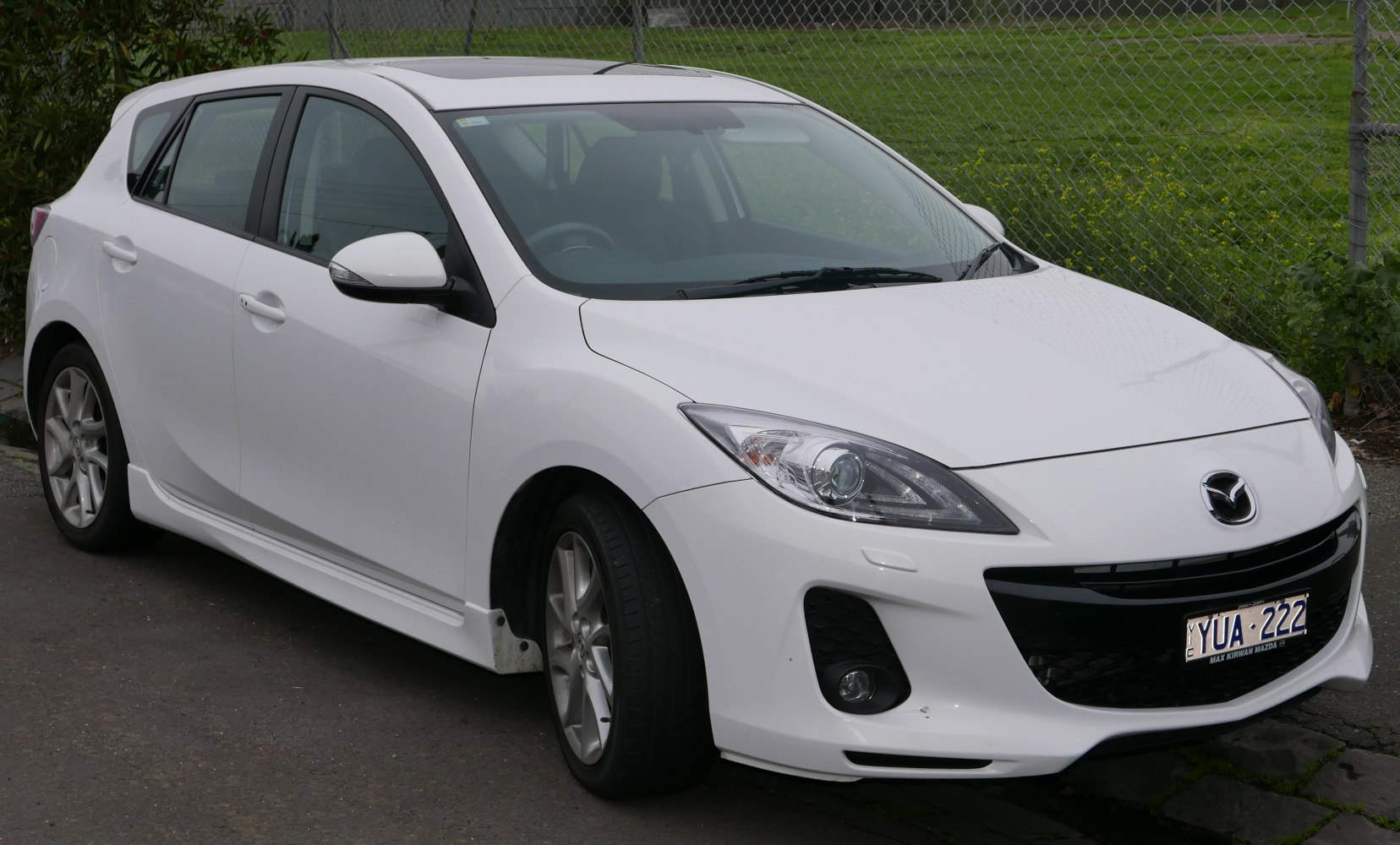 Front-side view of white hatchback with sharp headlights and sporty design