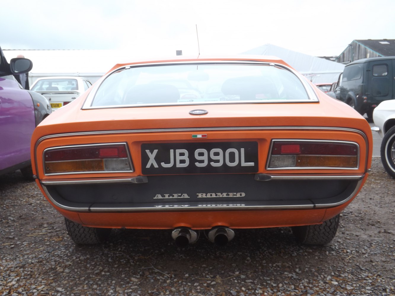 Rear view with tail lights and dual exhausts on a classic orange sports coupe