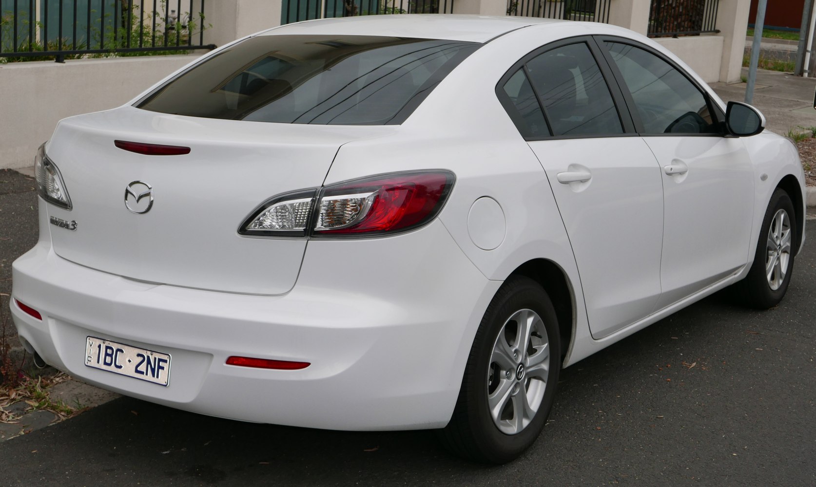 Rear-side view of white sedan with updated taillights and four doors