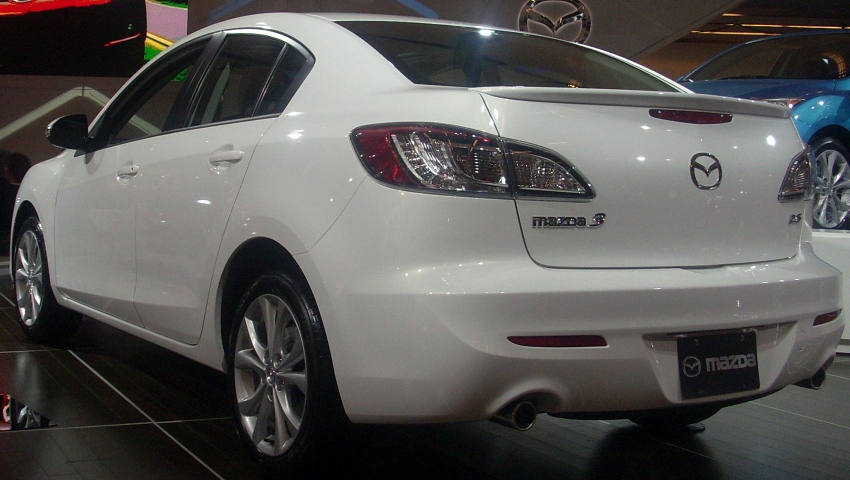 Rear-left view of sedan with taillights and rear wheel visible