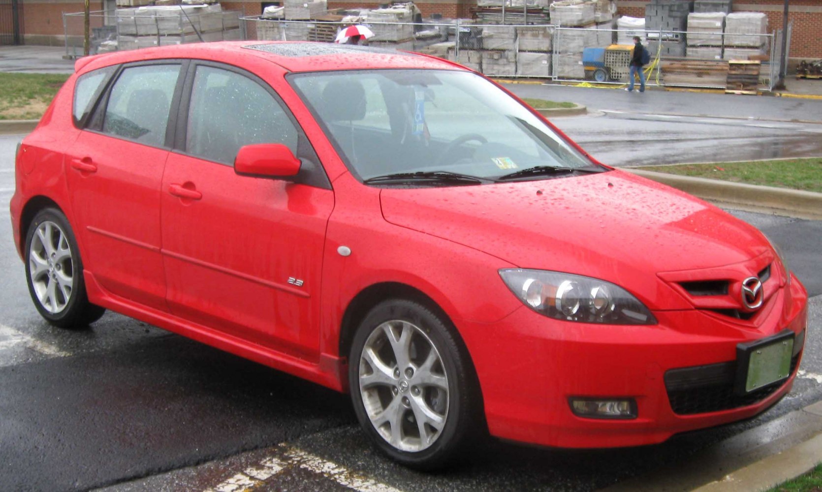 Red hatchback with sleek headlights and alloy wheels, front-side view