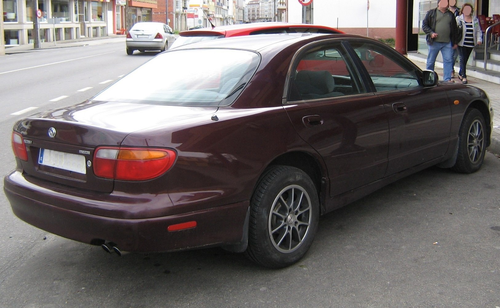 Rear and side view of a classic mid-90s sedan with dual exhaust and alloy wheels