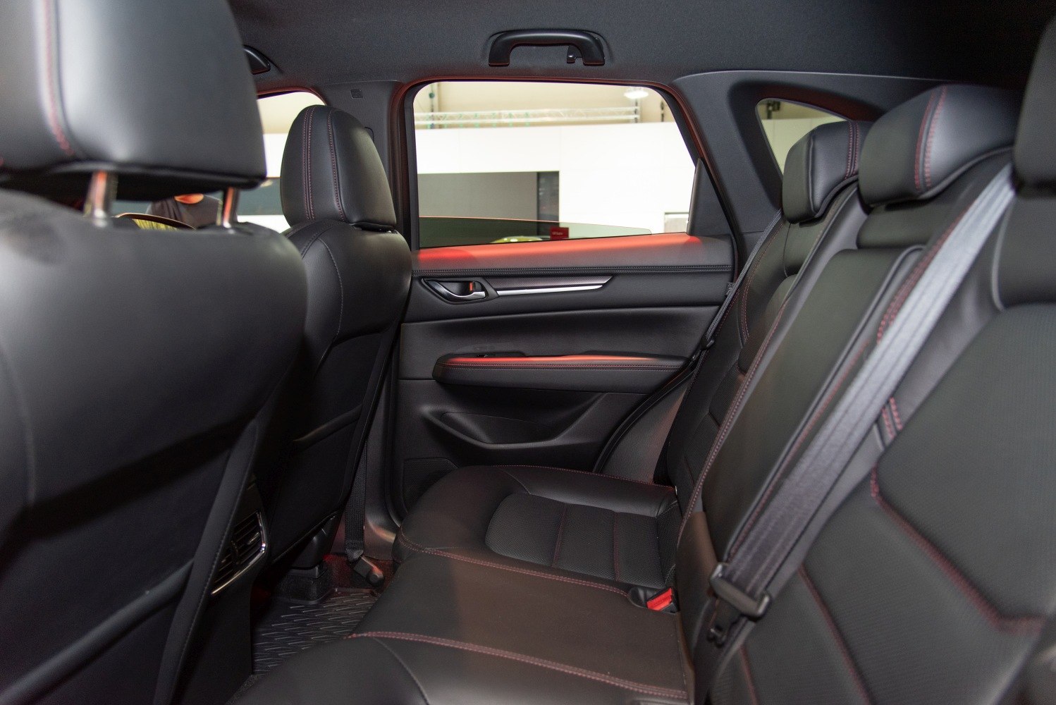 Black leather rear seats with red stitching and spacious interior door panel.