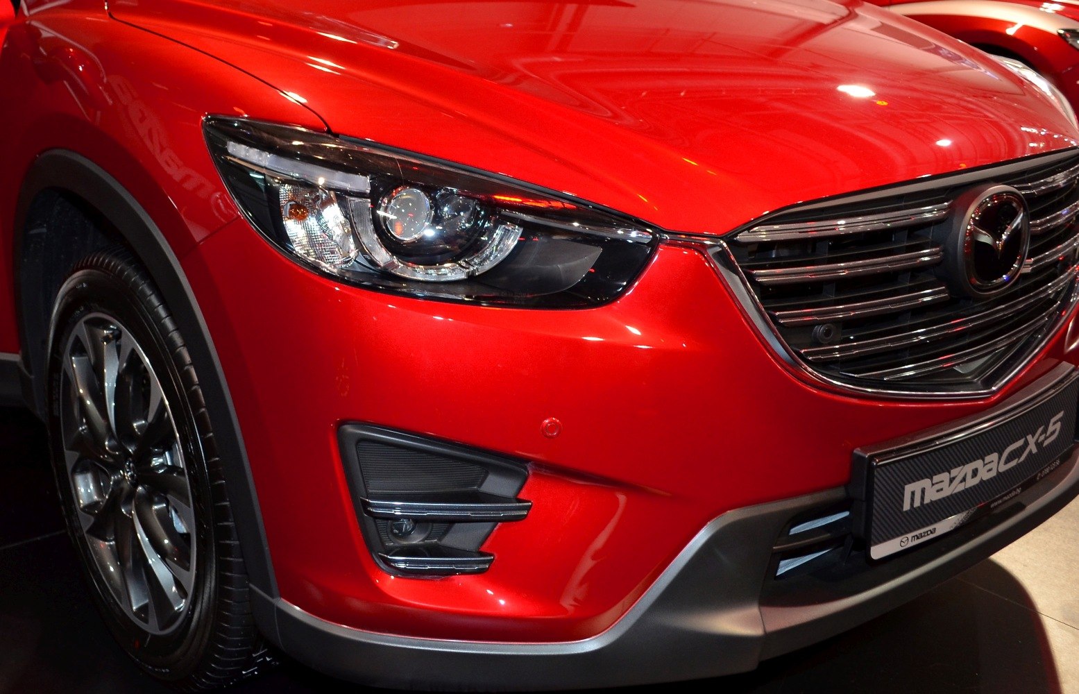 Close-up of front headlight, grille, fog light, and alloy wheel