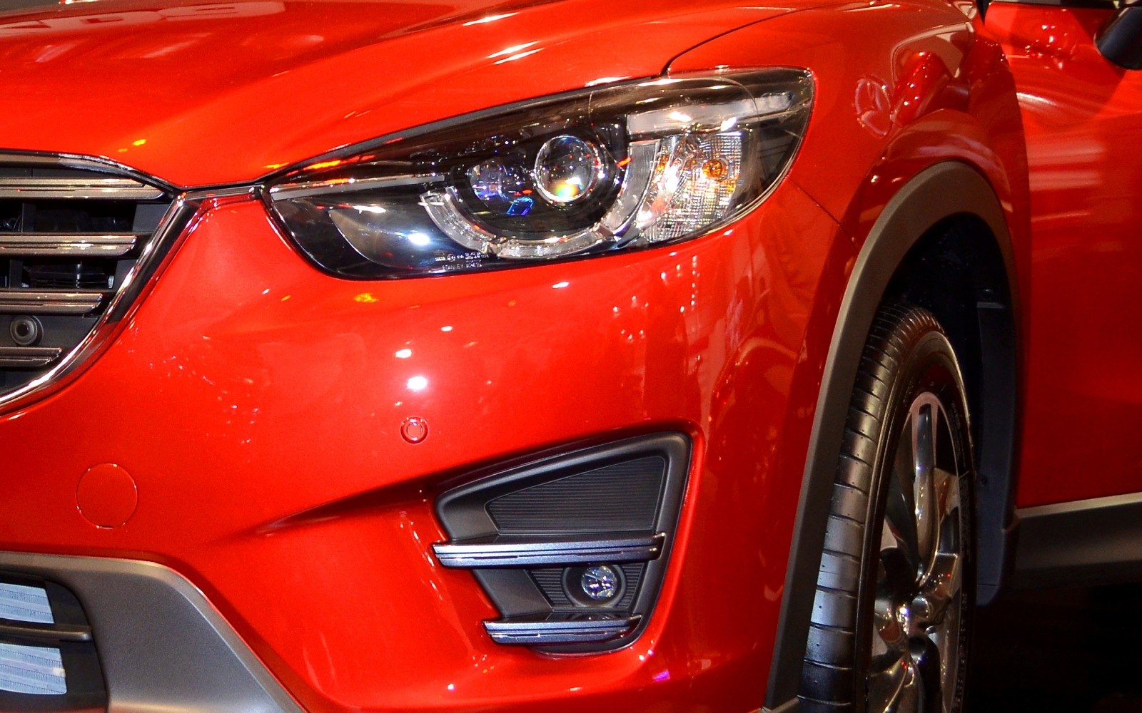 Close-up of front headlight and wheel of bright red vehicle