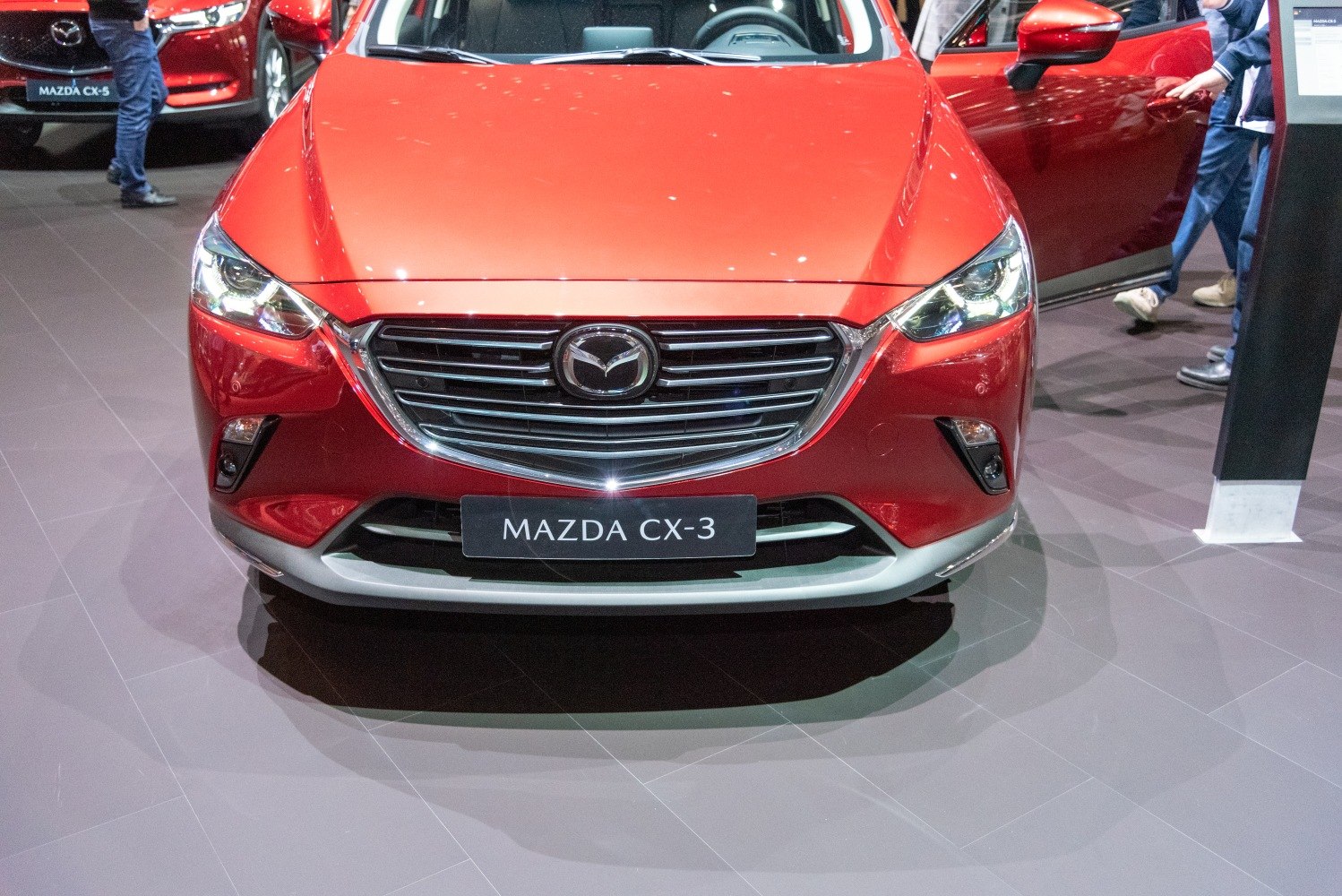 Front grille and headlights of a red vehicle at an auto show