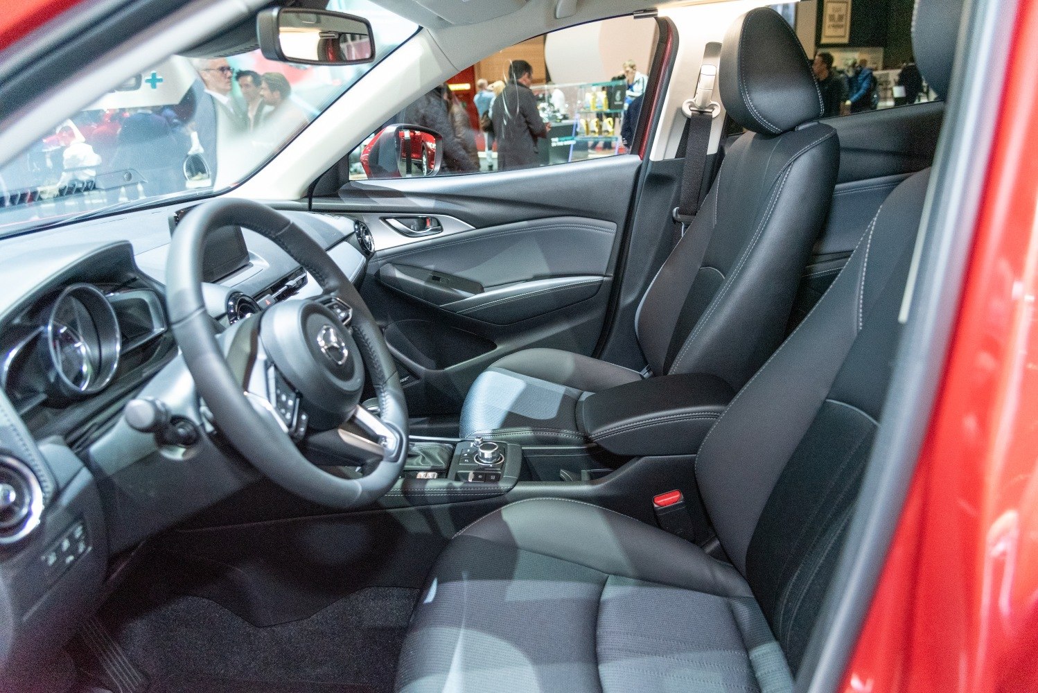 Modern car interior with steering wheel, dashboard, and black leather seats.