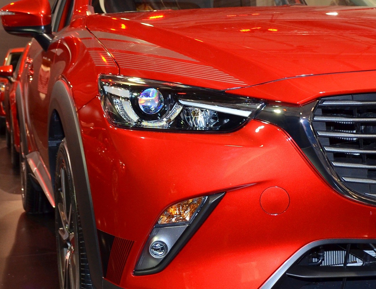 Close-up of front headlight, grille, and bumper with red sporty finish