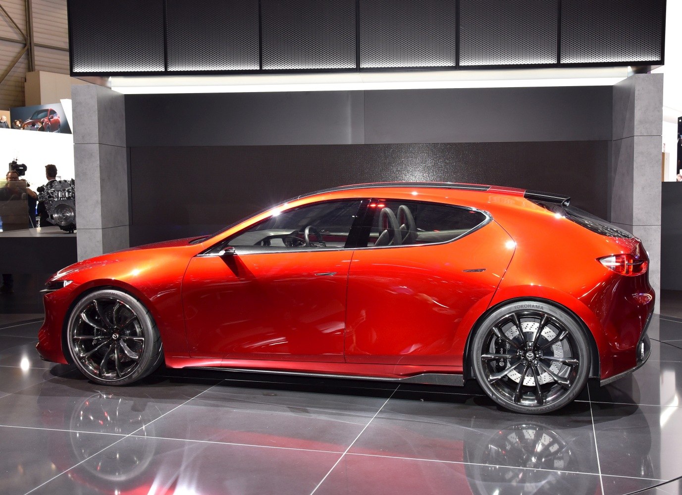 Sleek red hatchback with aerodynamic shape and large black multi-spoke wheels.