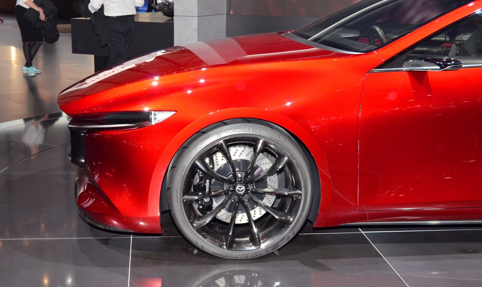 Close-up of front wheel, black multi-spoke alloy rim and red fender