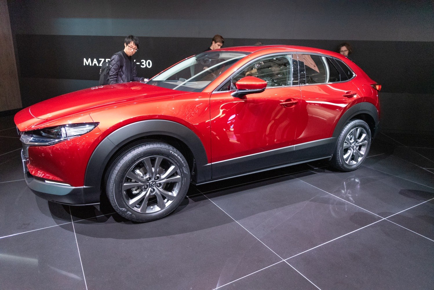 Side profile of a sleek red SUV with alloy wheels and smooth design lines.