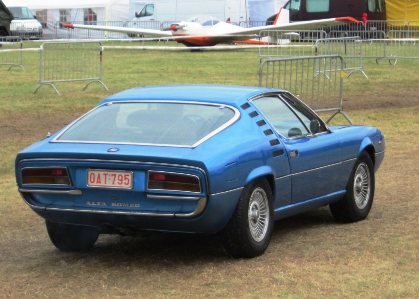 Rear view of a blue classic sports coupe with vented C-pillar and rectangular tail lights.