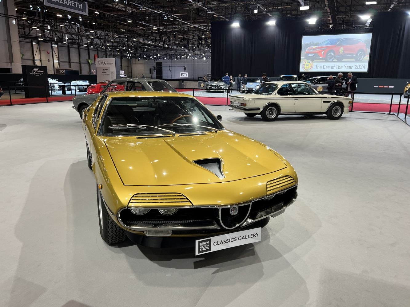 Golden vintage sports car with covered headlights and distinctive front grille.