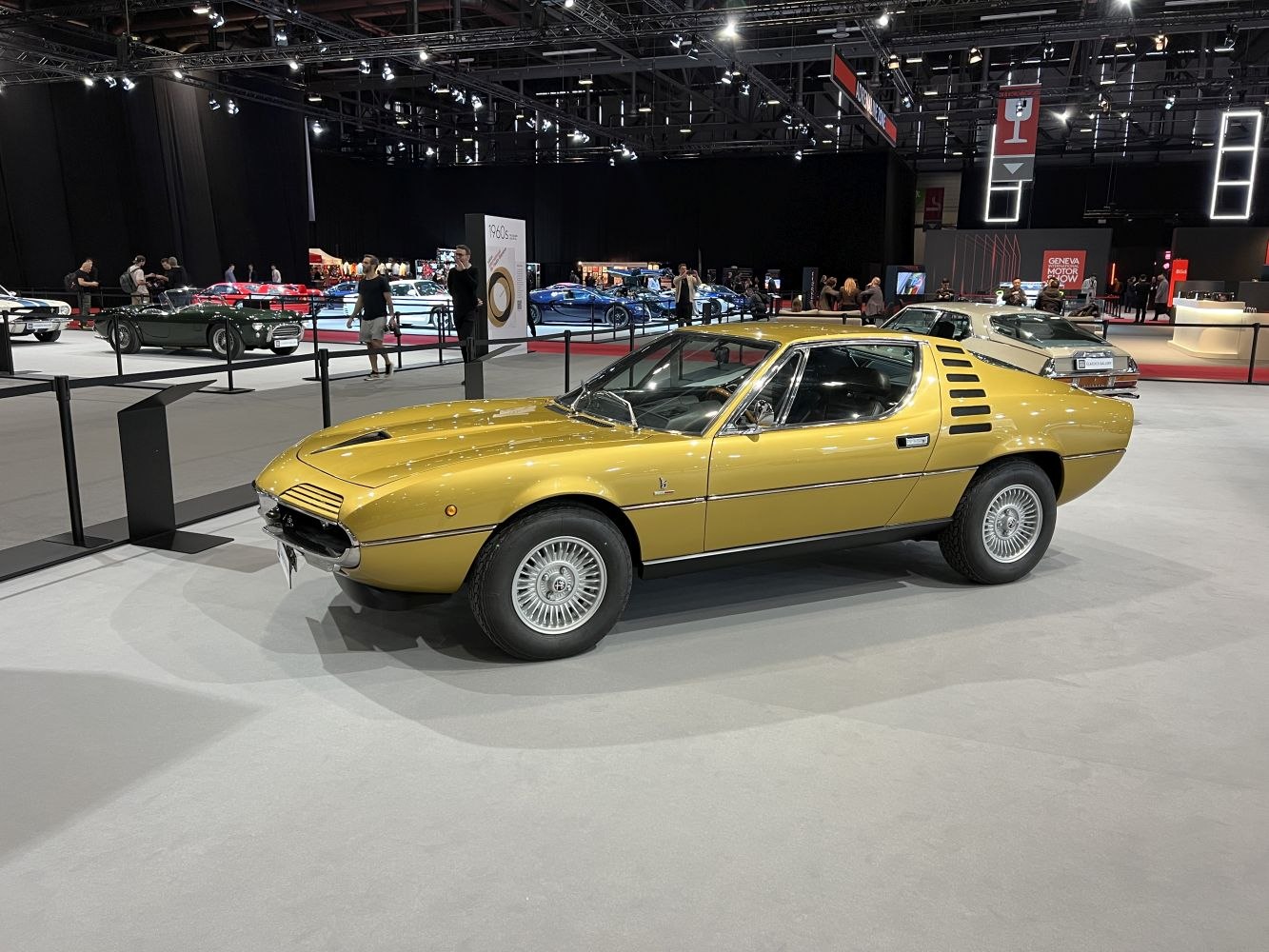 Classic sports coupe with rear window louvers and vintage alloy wheels.