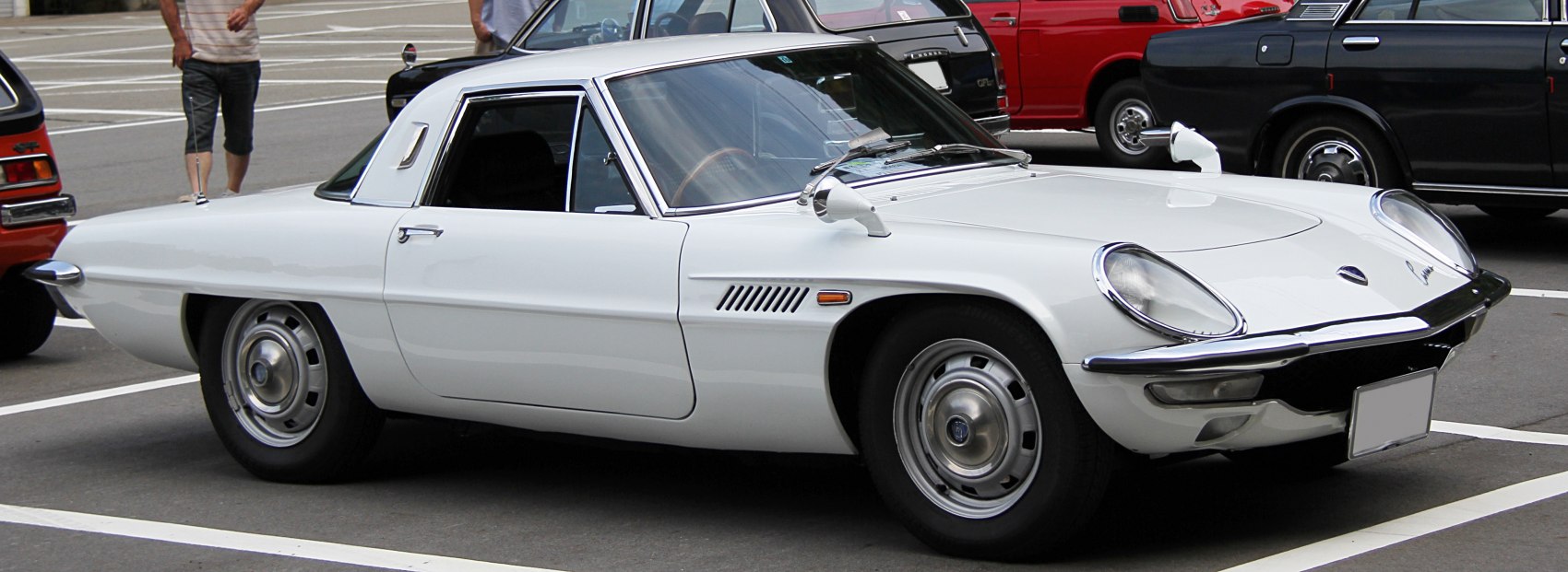 Classic vintage sports coupe with round headlamps and chrome bumpers in white.