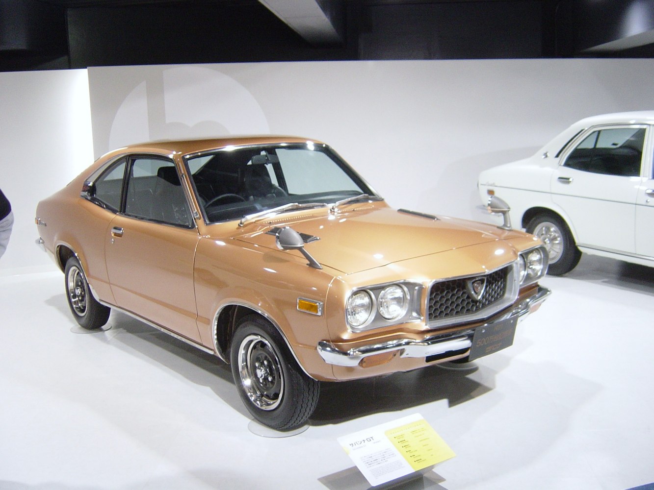 Vintage coupe with distinctive front grille, dual round headlights, and fender-mounted mirrors