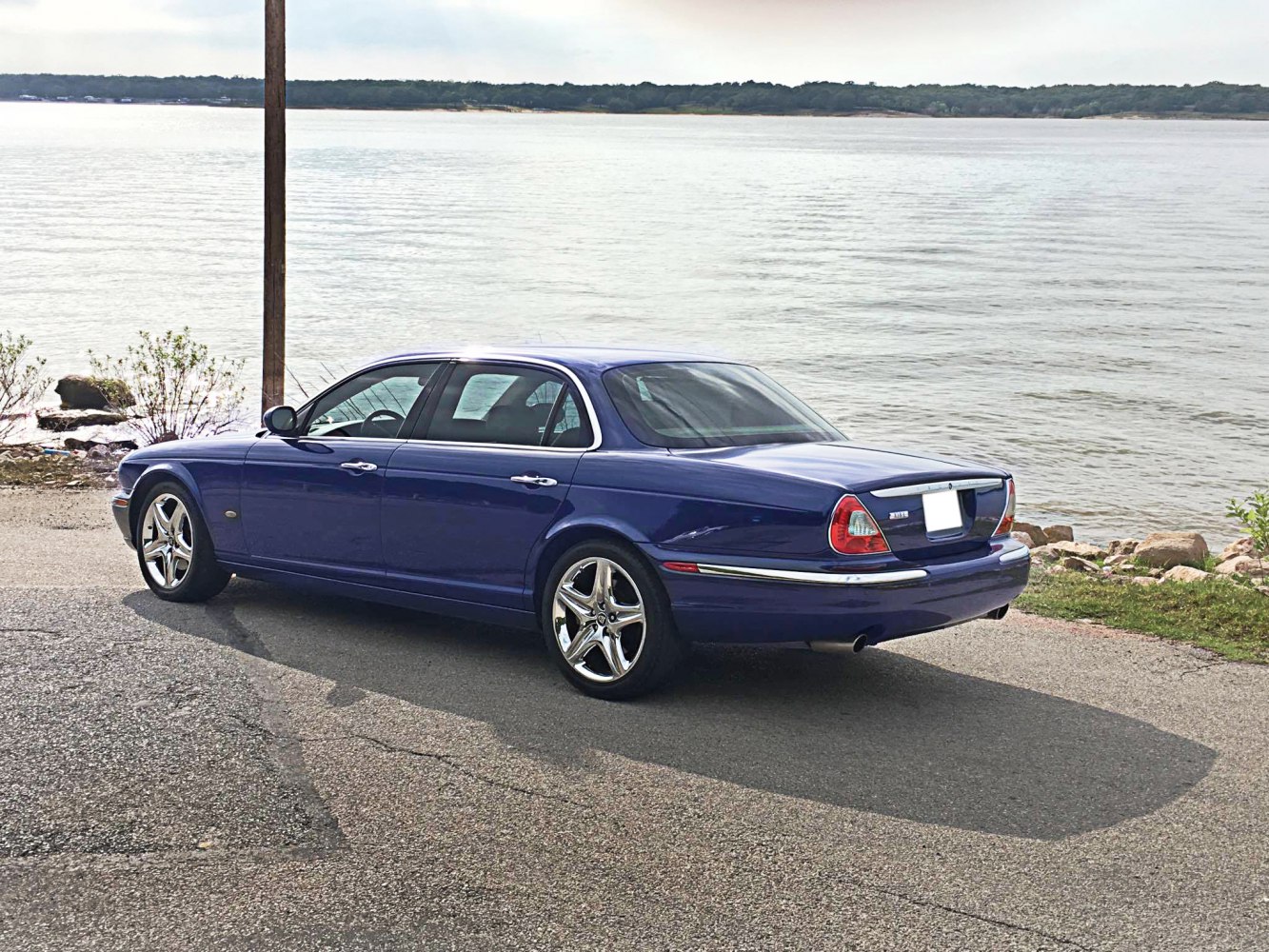 Rear side view of a blue luxury sedan with distinctive taillights and chrome detailing.
