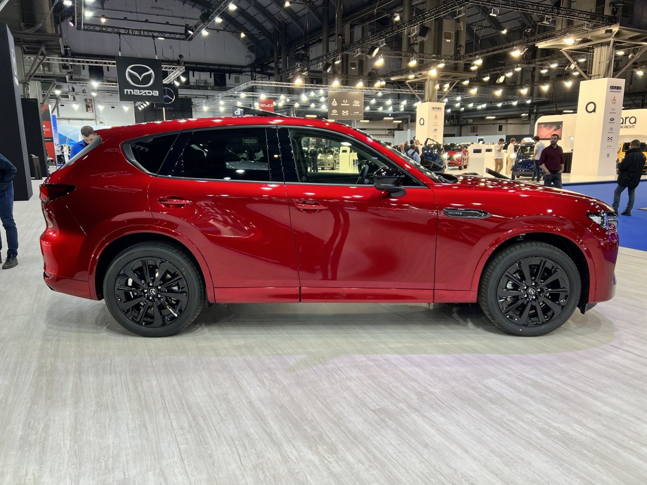 Red SUV with black alloy wheels in bright auto show setting