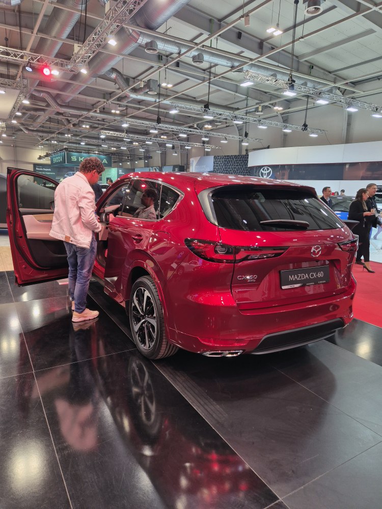 Rear view and open driver door of a red SUV in an exhibition hall
