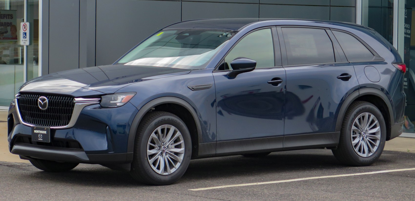 Dark blue SUV with large grille and alloy wheels parked by building