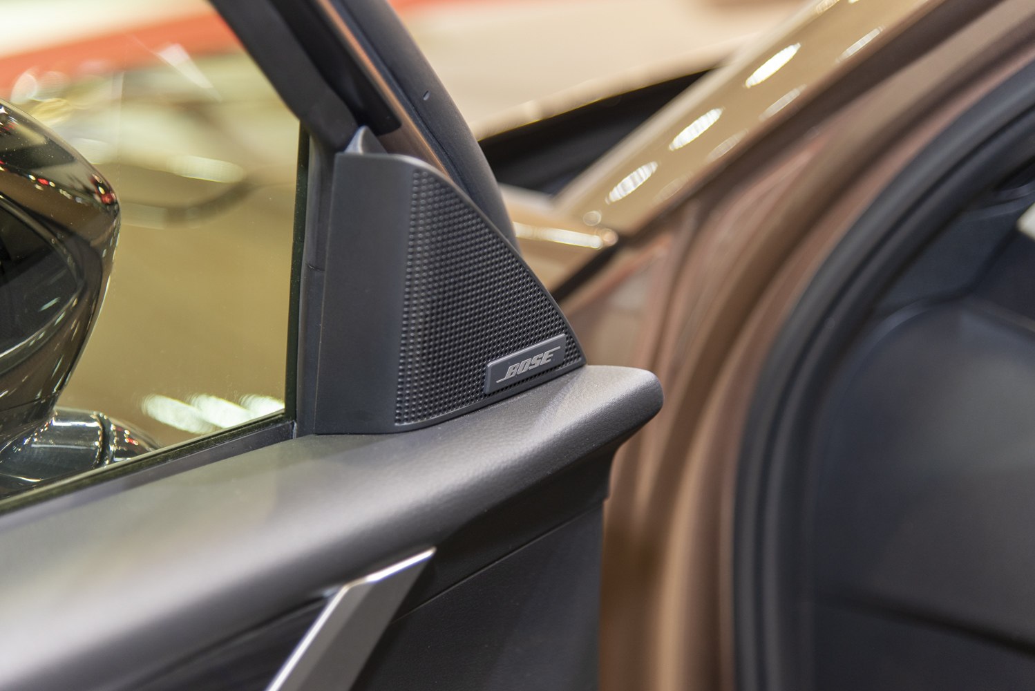 Close-up of a Bose speaker mounted on an interior car door panel.