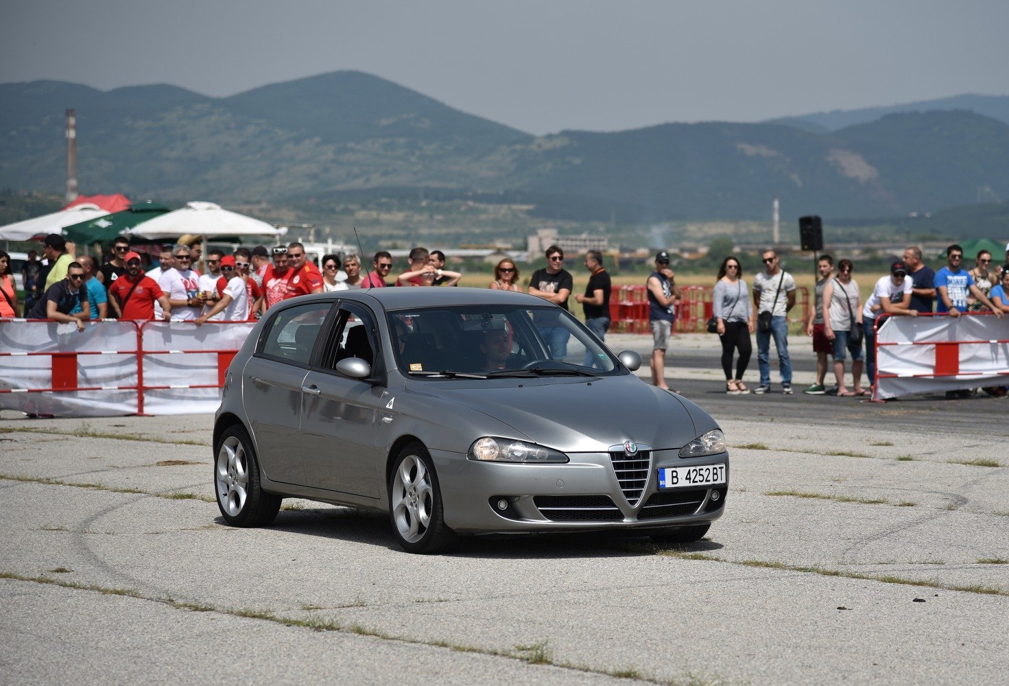 Silver 5-door hatchback in motion with crowd background