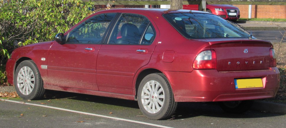 Rear and side view of a red hatchback with taillights and alloy wheels.