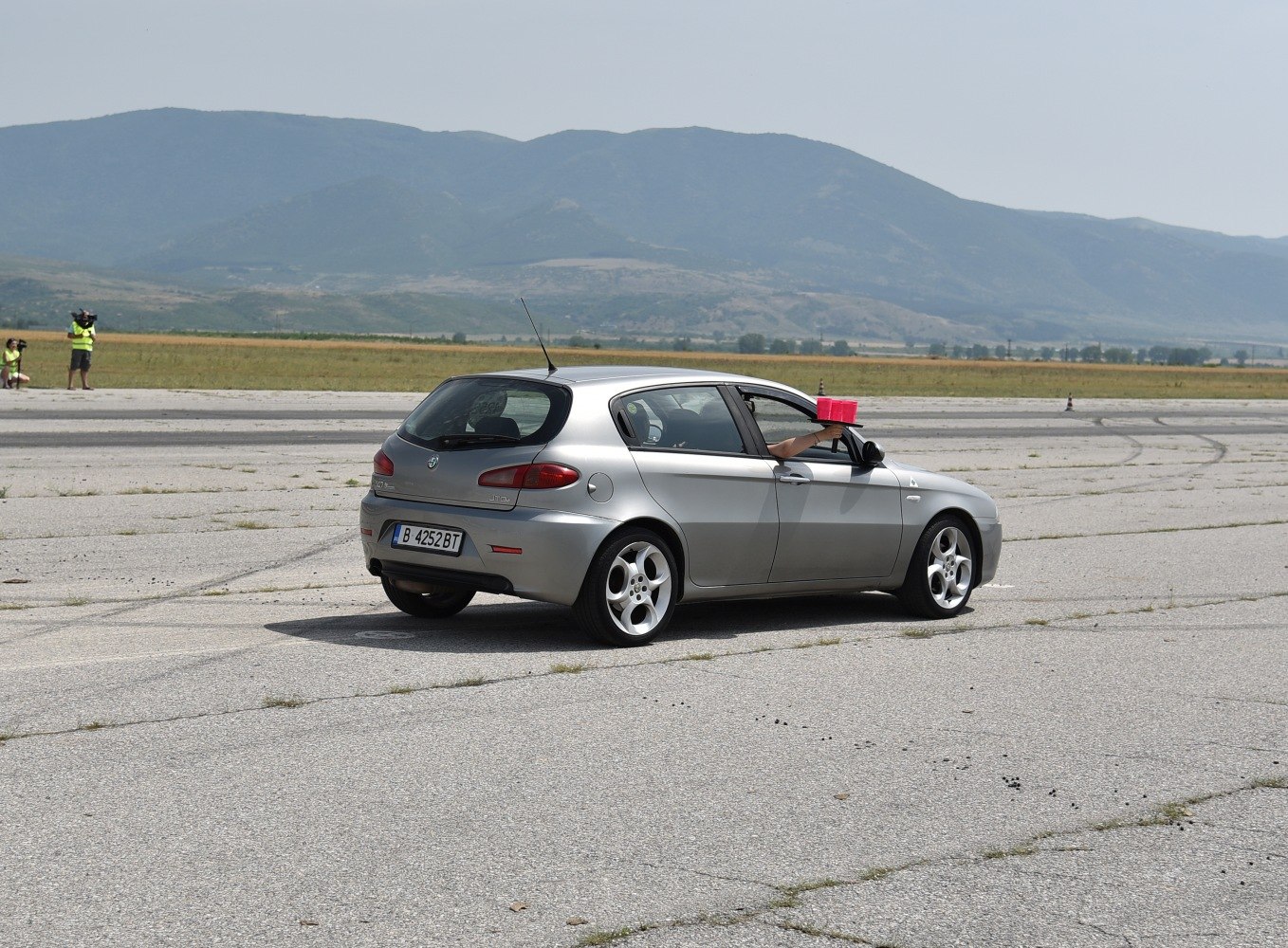 Silver 5-door hatchback rear view on cracked asphalt track