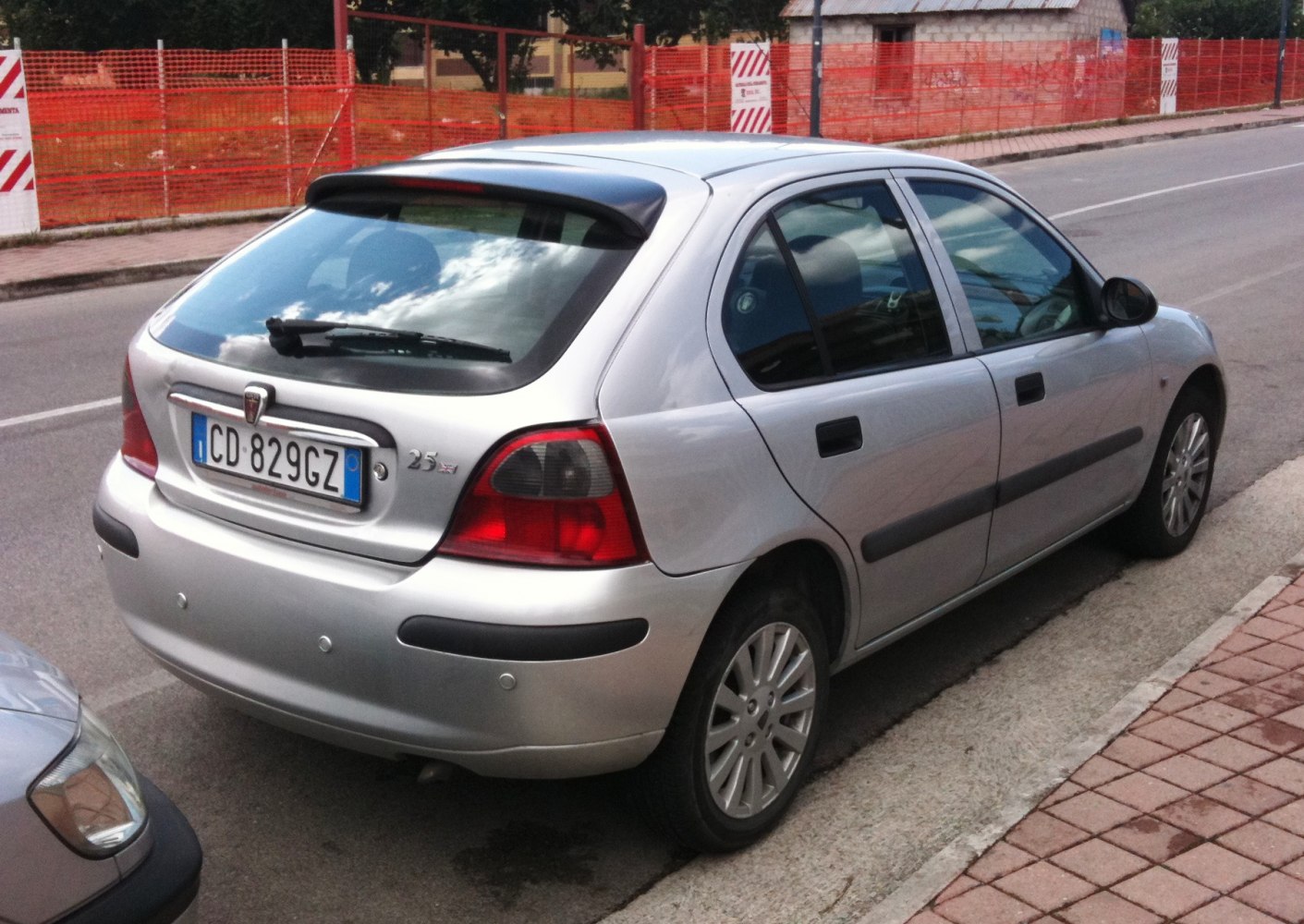 Silver 5-door hatchback rear side with spoiler and distinct tail lights
