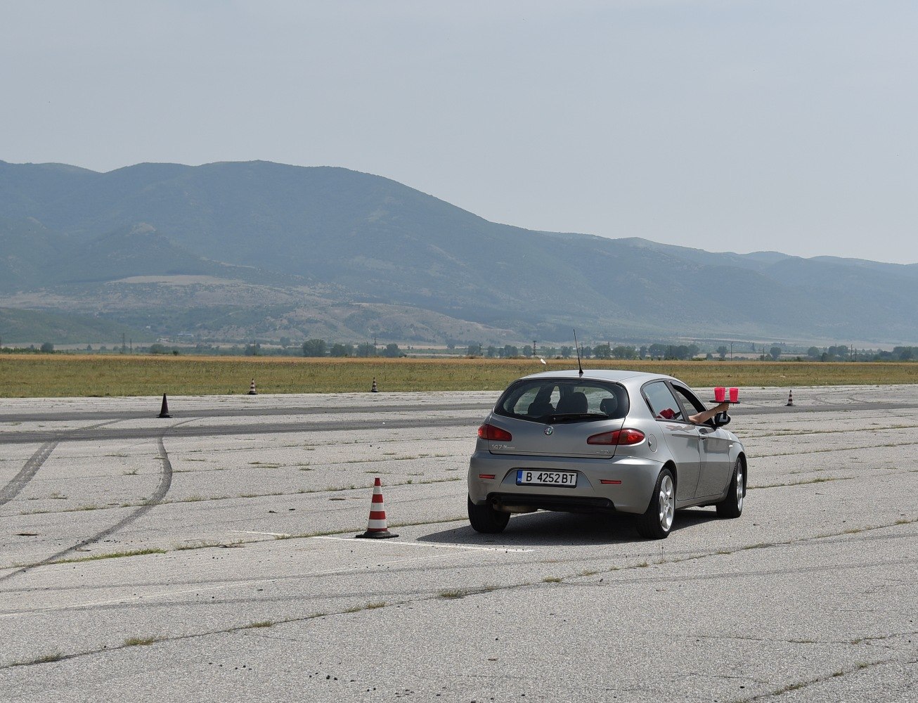 Rear view of a hatchback on open air track with mountains