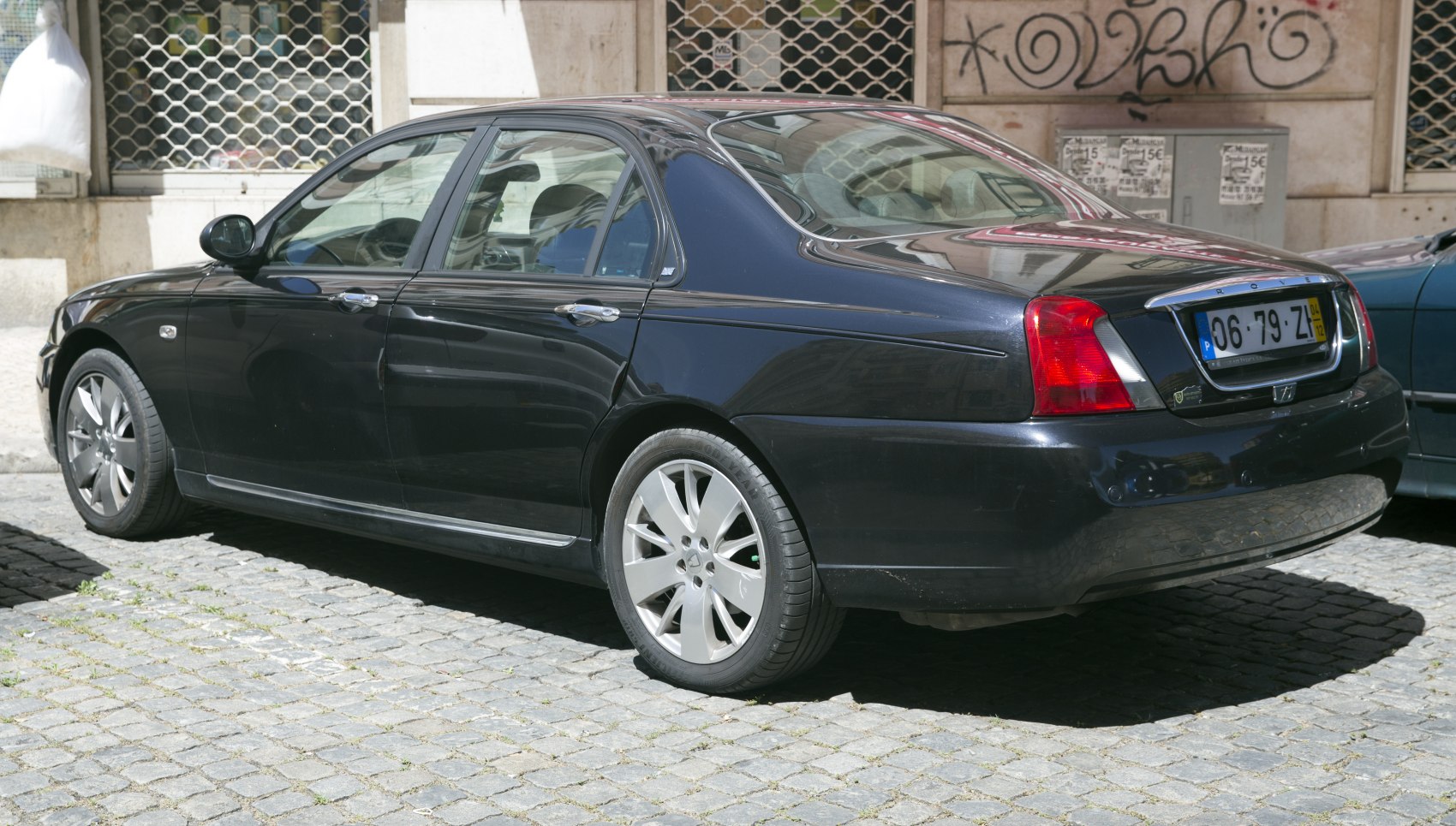 Rear side profile of a black sedan with alloy wheels and distinct rear lights